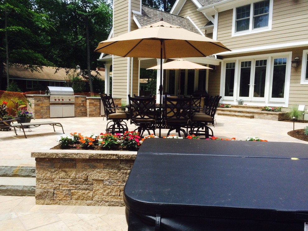 Immagine di un patio o portico american style di medie dimensioni e dietro casa con pavimentazioni in pietra naturale e un parasole