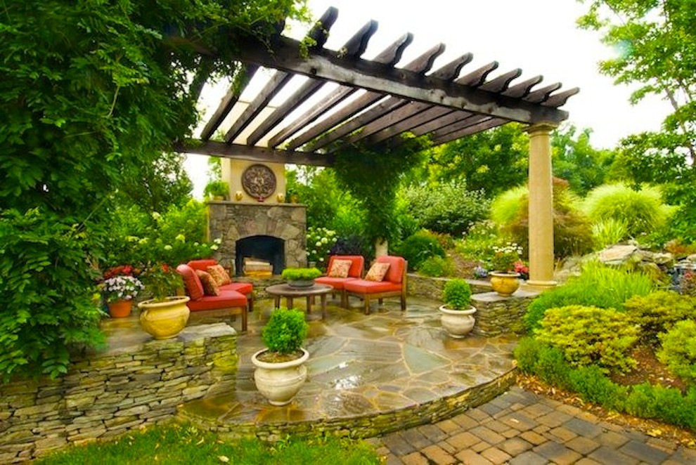 Patio - mediterranean backyard stone patio idea in DC Metro with a fireplace and a pergola