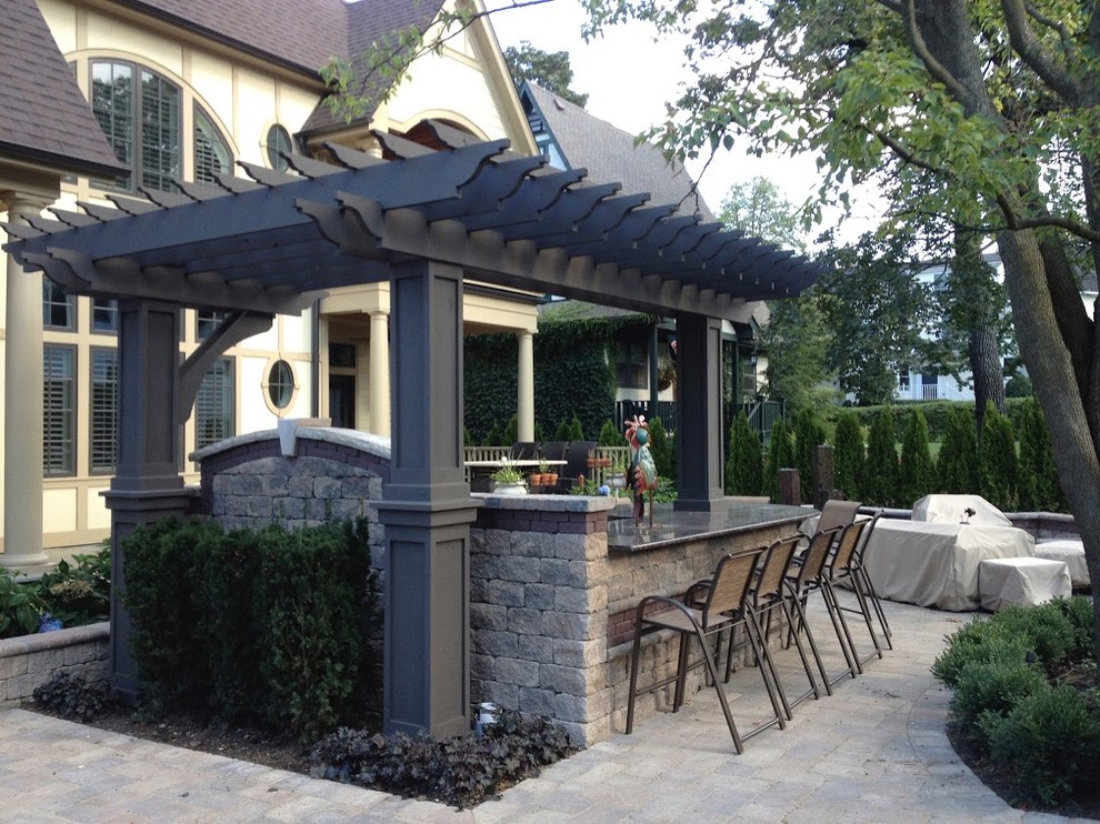 Ejemplo de patio clásico de tamaño medio en patio trasero con cocina exterior, adoquines de hormigón y pérgola