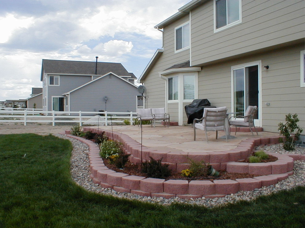 Example of a mid-sized classic backyard stone patio design in Denver with no cover