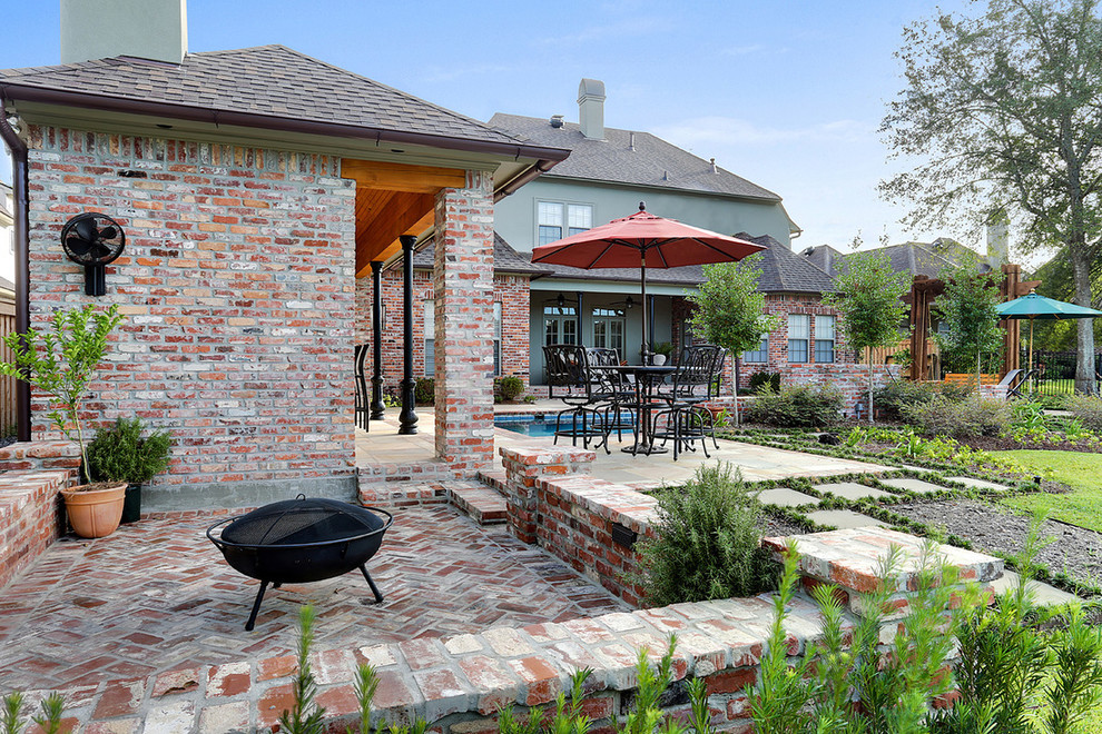 Foto di un patio o portico classico di medie dimensioni e dietro casa con un focolare, pavimentazioni in mattoni e nessuna copertura