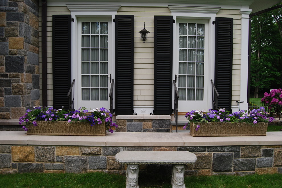 Imagen de patio de estilo americano grande sin cubierta en patio trasero con jardín de macetas y adoquines de piedra natural