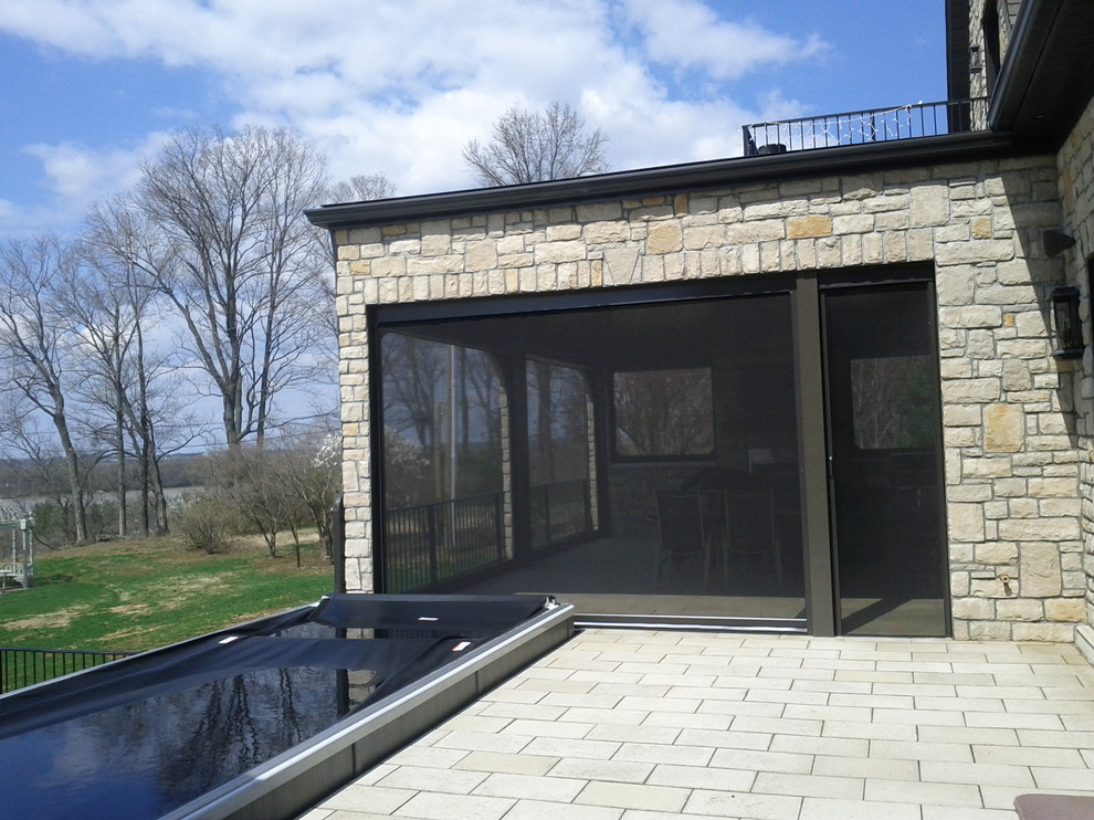 Foto di un grande patio o portico chic dietro casa con pavimentazioni in cemento e un tetto a sbalzo