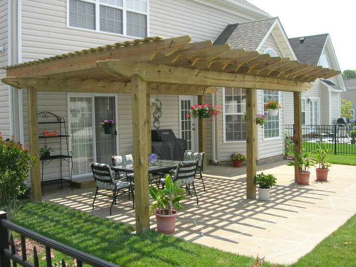Esempio di un patio o portico chic di medie dimensioni e dietro casa con cemento stampato e una pergola