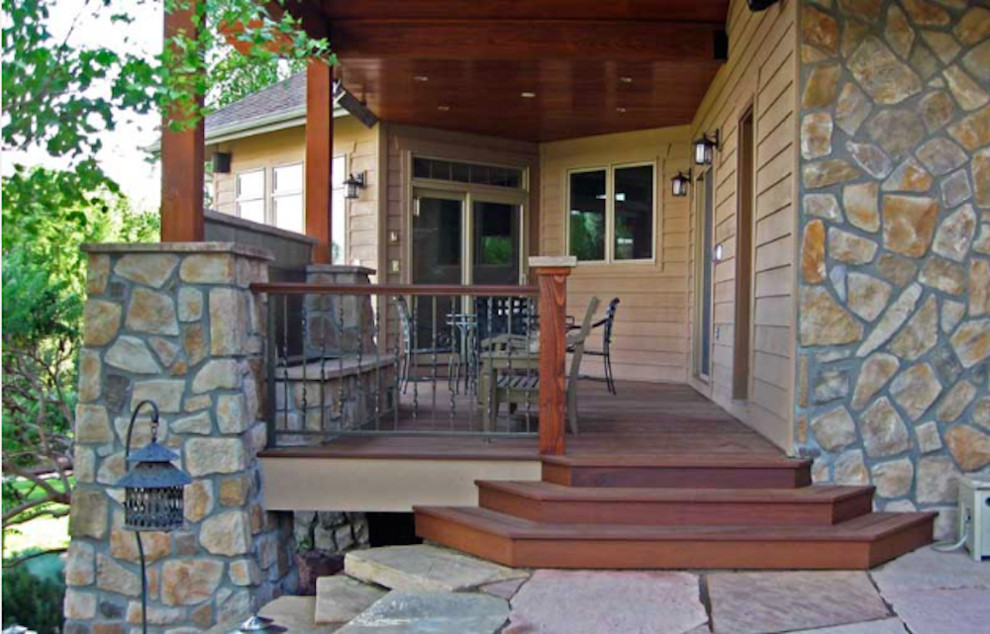 Example of a mid-sized mountain style backyard stone patio design in Denver with a roof extension