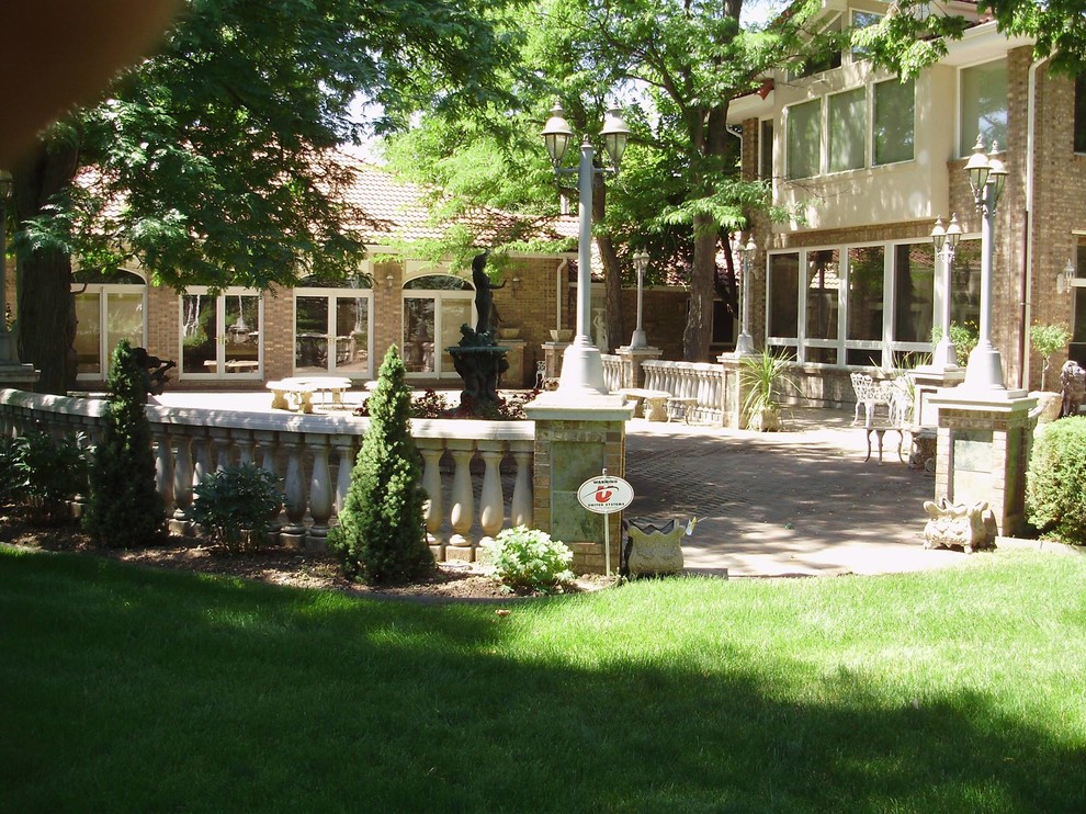 This is an example of an expansive traditional back patio in Denver with a water feature and stamped concrete.