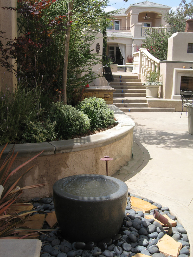 This is an example of a large contemporary courtyard patio in Boise with a water feature, stamped concrete and an awning.