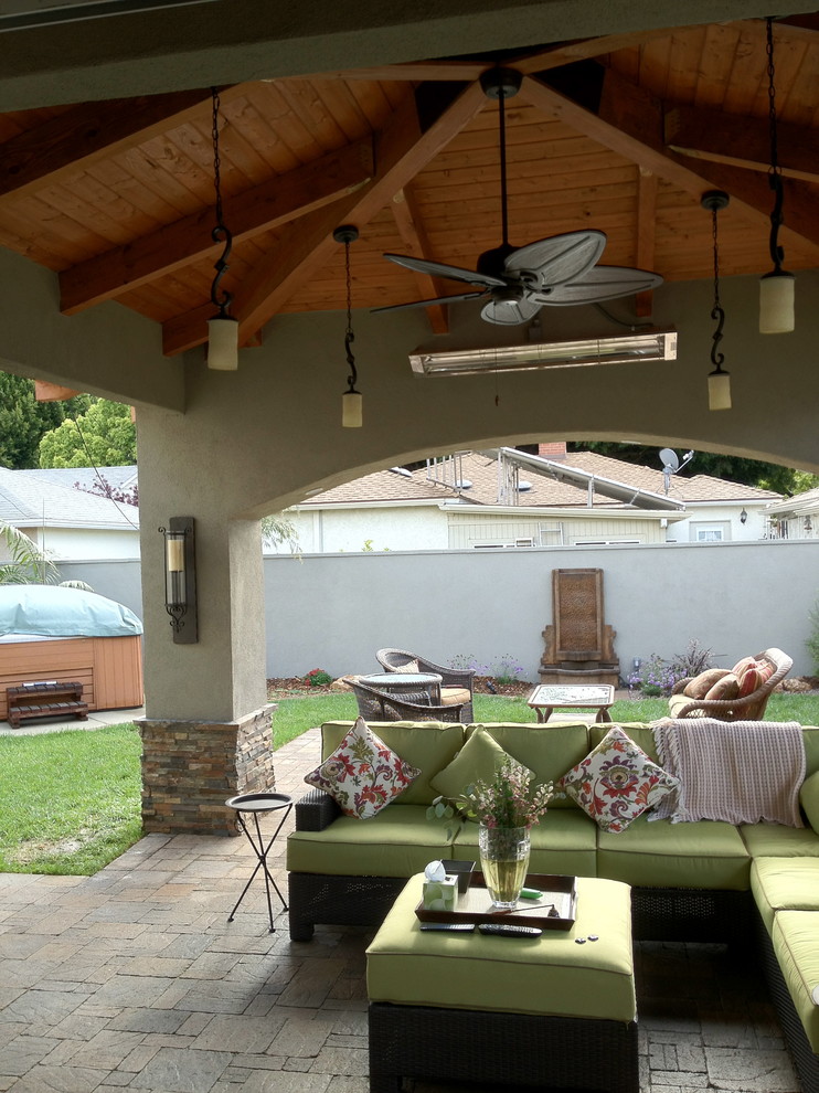 Example of a mid-sized tuscan backyard stone patio design in Los Angeles with a roof extension