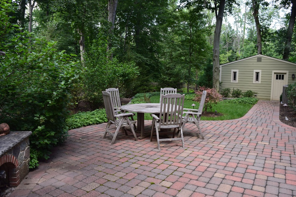 This is an example of a large classic back patio in New York with a fire feature, brick paving and no cover.