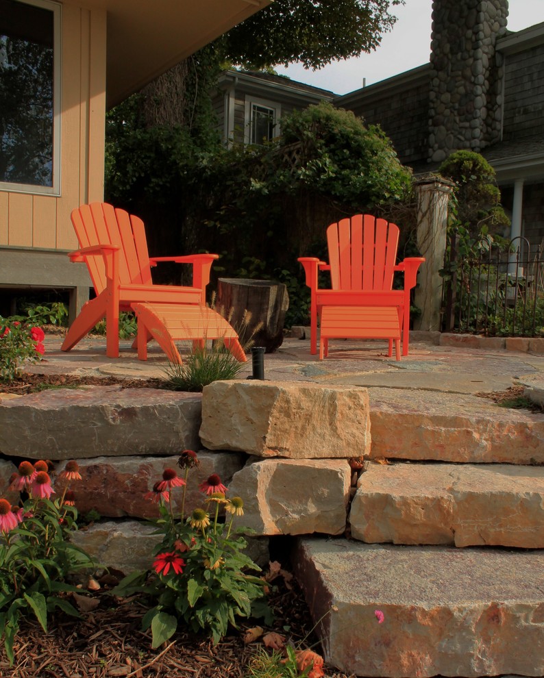 Photo of a large rustic back patio in Grand Rapids with natural stone paving and no cover.
