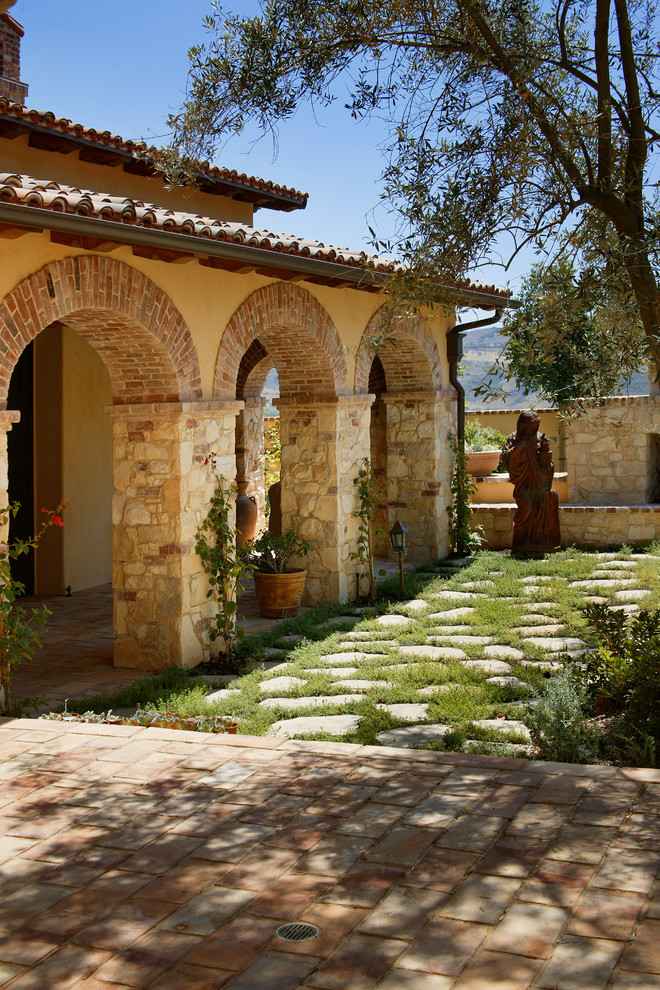 Diseño de patio mediterráneo en patio trasero y anexo de casas con adoquines de hormigón