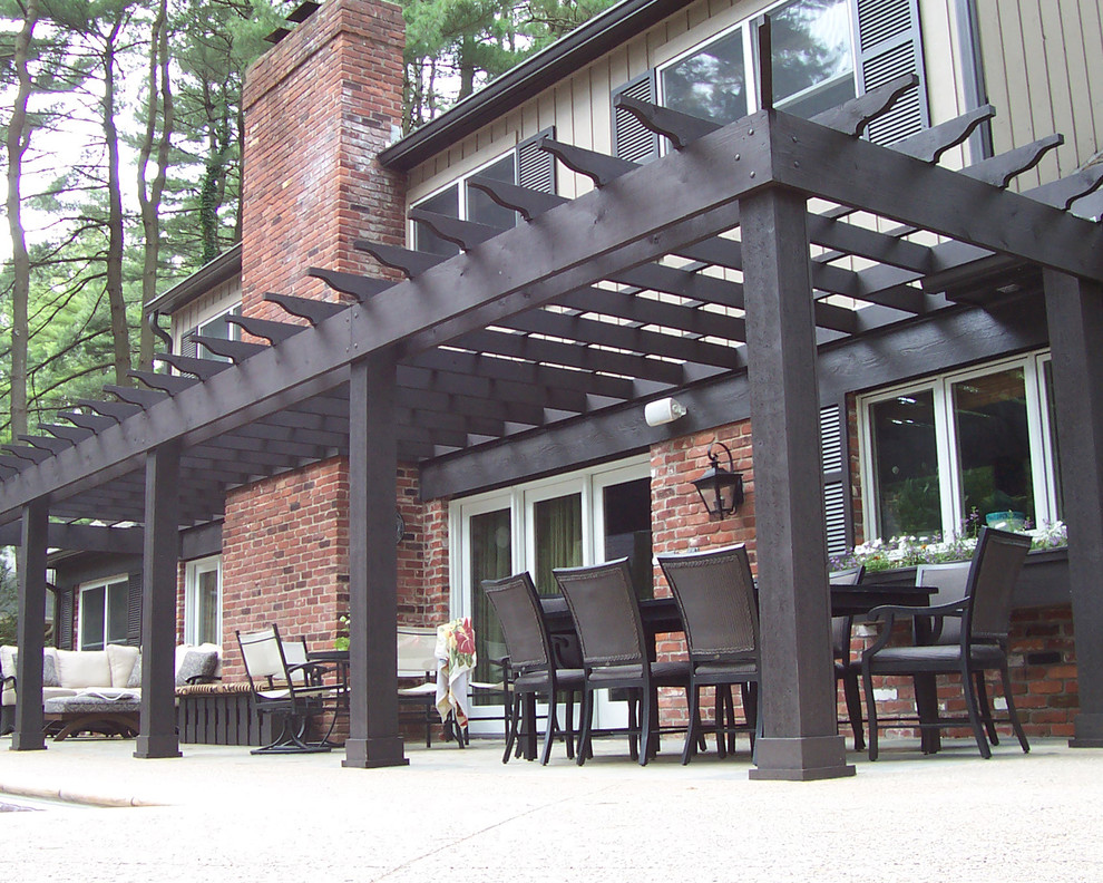 Idee per un patio o portico tradizionale di medie dimensioni e dietro casa con lastre di cemento e una pergola