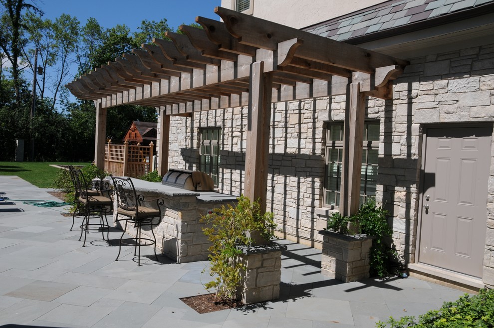 Imagen de patio clásico renovado de tamaño medio en patio lateral con cocina exterior, adoquines de hormigón y pérgola