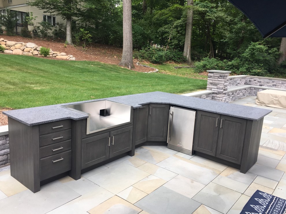 This is an example of a medium sized classic back patio in New York with an outdoor kitchen, stamped concrete and no cover.