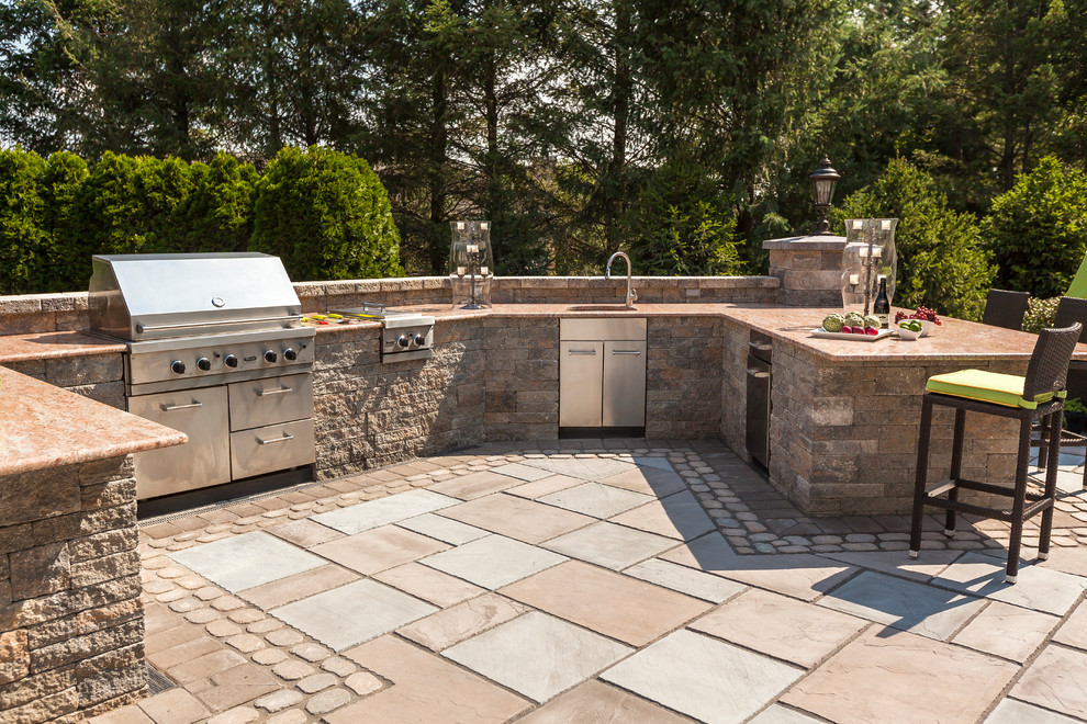 This is an example of a large traditional back patio in Minneapolis with an outdoor kitchen, concrete paving and no cover.