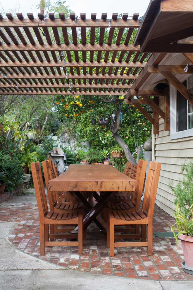 Foto di un patio o portico stile rurale di medie dimensioni e dietro casa con un giardino in vaso, pavimentazioni in mattoni e una pergola
