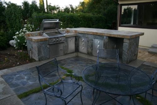 Cette photo montre une terrasse craftsman avec une cuisine d'été et des pavés en pierre naturelle.