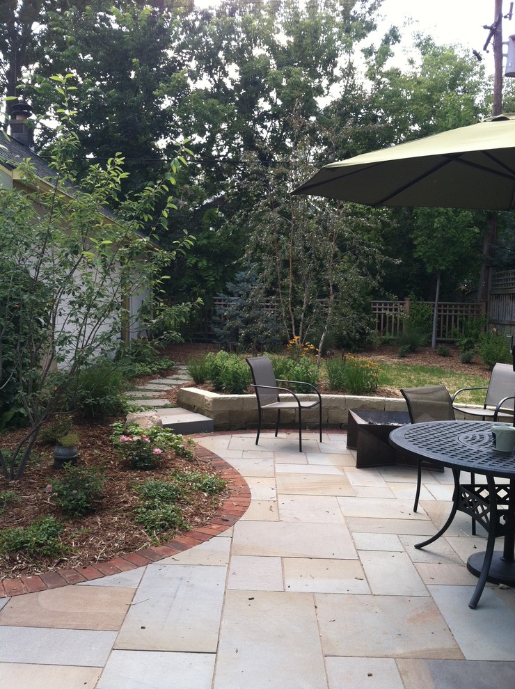 Aménagement d'une terrasse arrière romantique de taille moyenne avec des pavés en pierre naturelle, un foyer extérieur et un auvent.