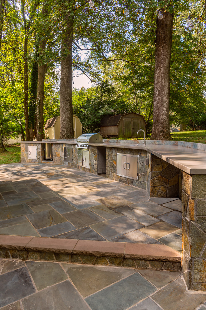 Exemple d'une grande terrasse arrière tendance avec une cuisine d'été, des pavés en pierre naturelle et aucune couverture.