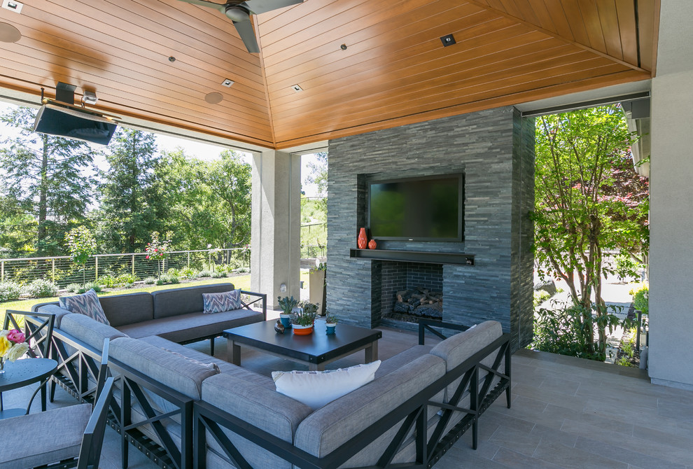 Large modern back patio in San Francisco with a fire feature, concrete paving and a roof extension.