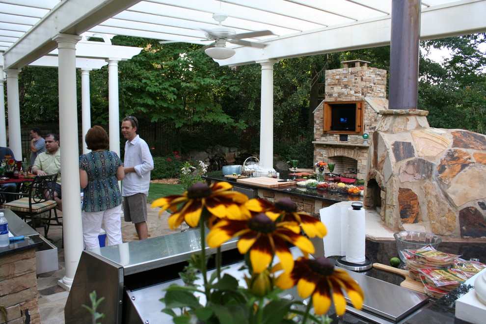 Modelo de patio clásico renovado grande en patio trasero con cocina exterior, adoquines de piedra natural y pérgola