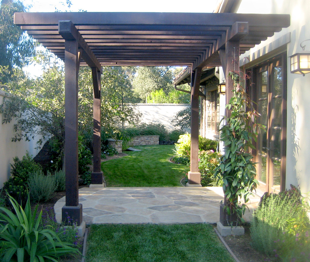 Cette image montre une petite terrasse minimaliste avec une cour, des pavés en pierre naturelle et une pergola.