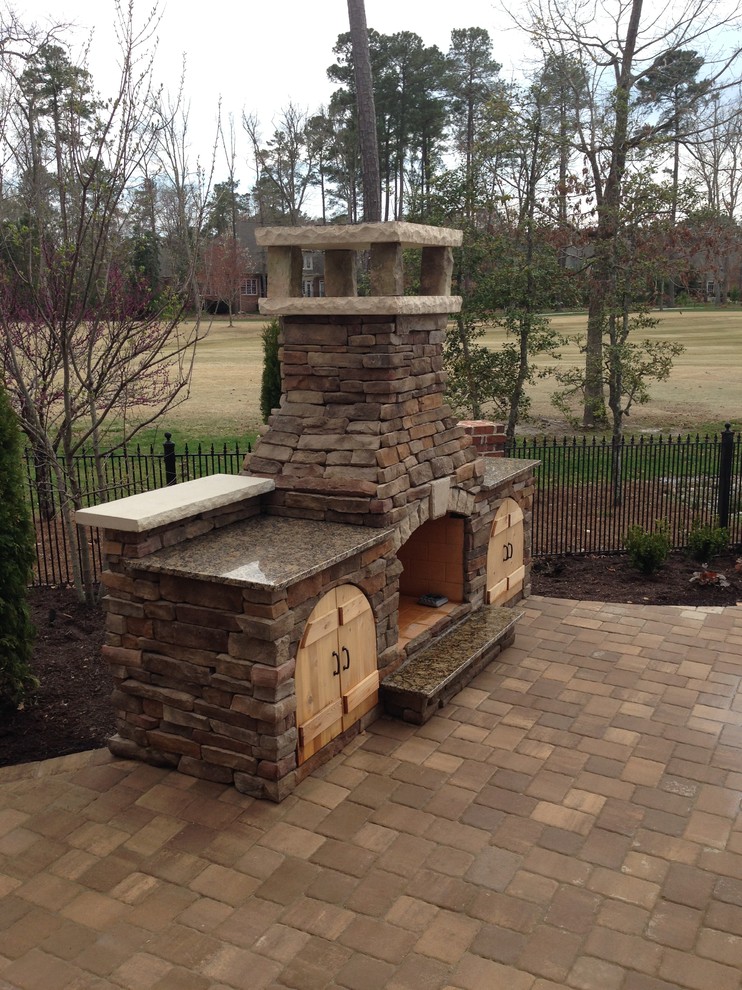 This is an example of a large classic back patio in Cincinnati with a fire feature, concrete paving and no cover.