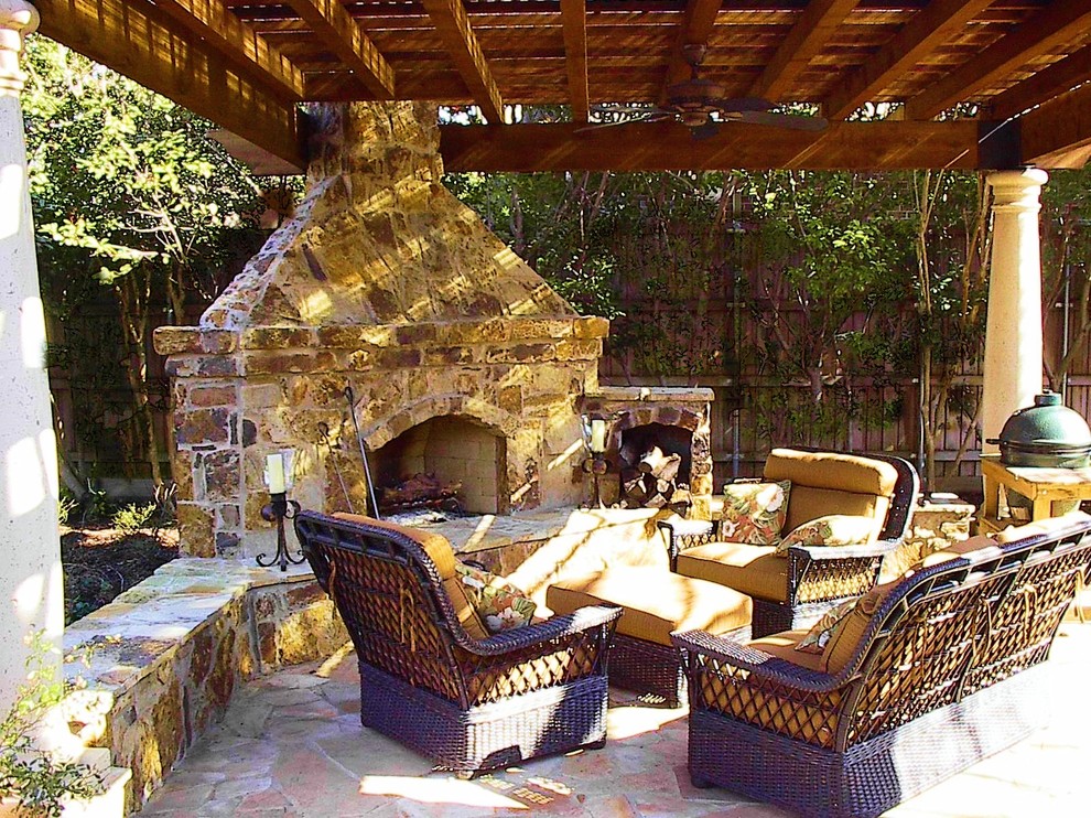 Esempio di un patio o portico stile rurale dietro casa con un focolare, pavimentazioni in pietra naturale e un tetto a sbalzo