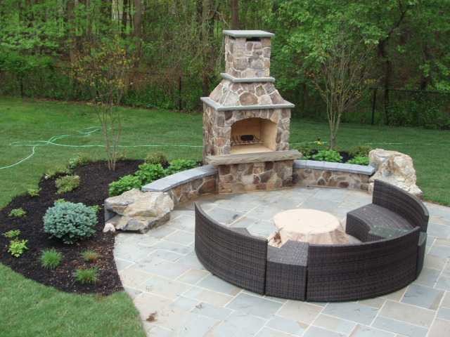 Imagen de patio de estilo de casa de campo grande sin cubierta en patio trasero con brasero y adoquines de piedra natural