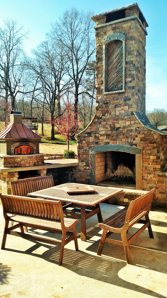 Foto di un grande patio o portico stile rurale dietro casa con un focolare, cemento stampato e nessuna copertura