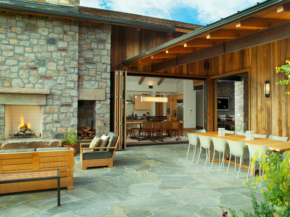 Mountain style stone patio photo in Denver with a fire pit and a roof extension