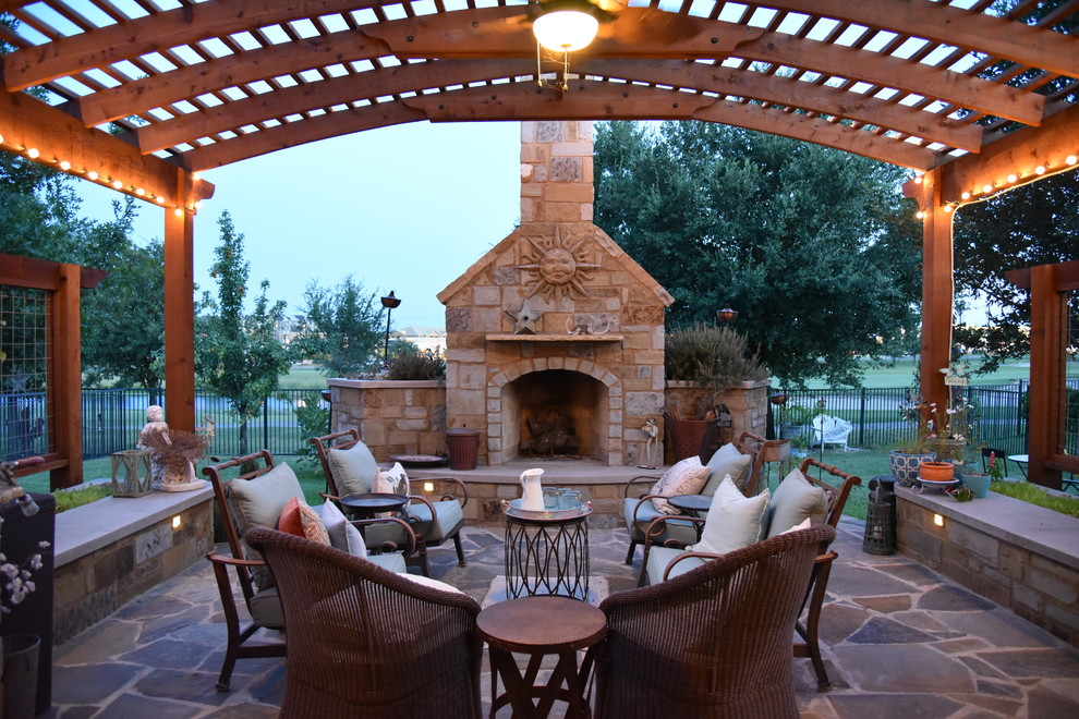 Inspiration for a large rustic back patio in Austin with a fire feature, natural stone paving and a pergola.