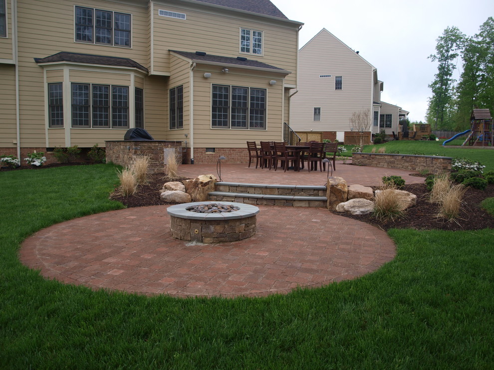 Example of a mid-sized classic backyard brick patio design in Richmond with a fire pit and no cover