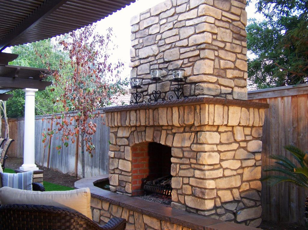 Cette photo montre une terrasse arrière craftsman de taille moyenne avec une cheminée, du béton estampé et une pergola.