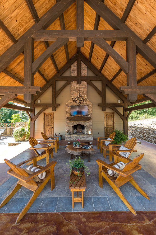 Inspiration for a large rustic back patio in Other with natural stone paving, a roof extension and a fireplace.