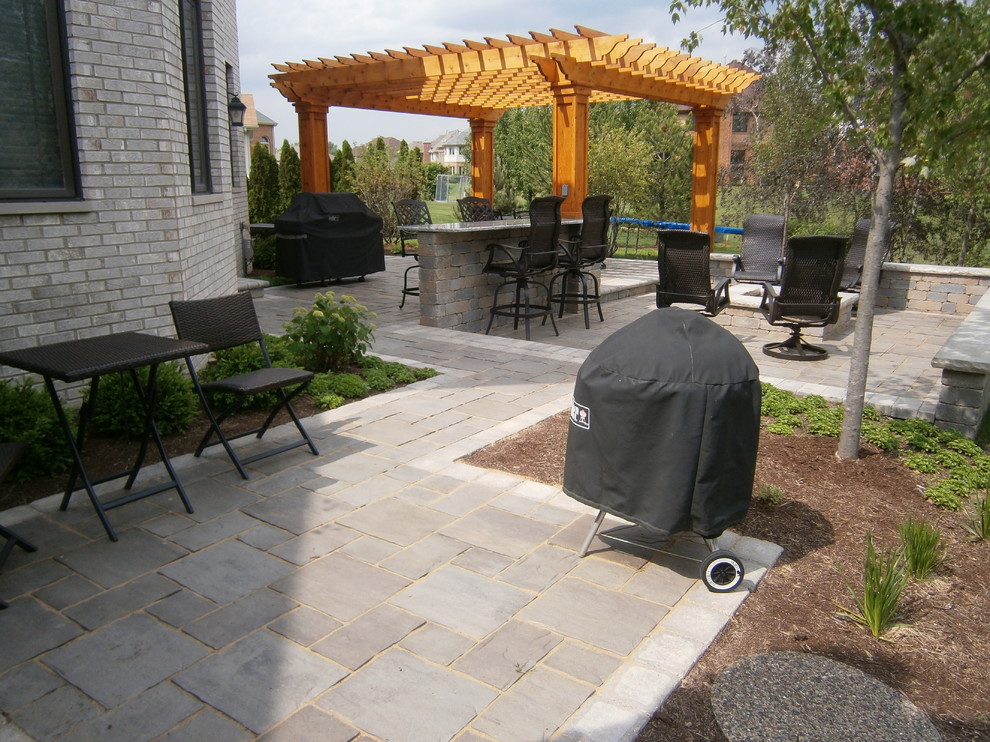Diseño de patio clásico en patio trasero con brasero, adoquines de ladrillo y pérgola