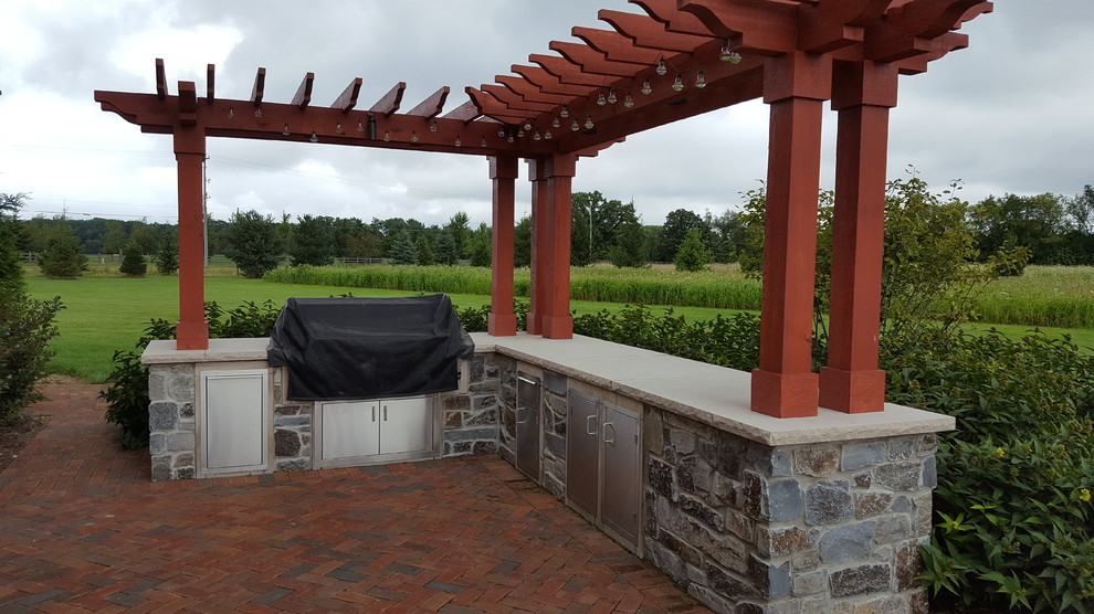 Inspiration for a large traditional back patio in Milwaukee with an outdoor kitchen, brick paving and a pergola.