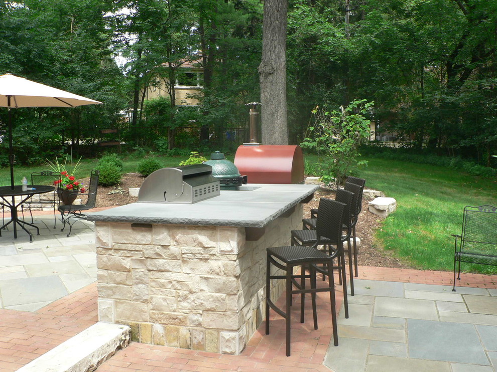 Medium sized rustic back patio in Milwaukee with an outdoor kitchen, natural stone paving and no cover.