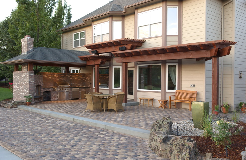 Réalisation d'une terrasse arrière tradition de taille moyenne avec une cuisine d'été, des pavés en béton et une extension de toiture.