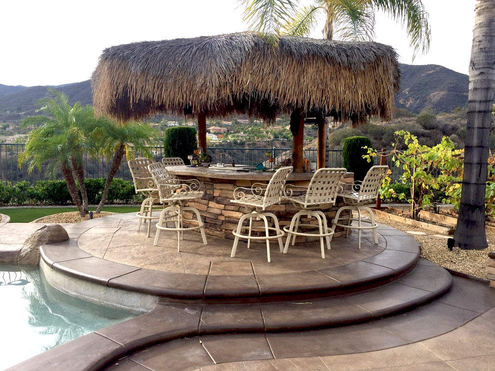 Inspiration for a large tropical backyard stamped concrete patio remodel in Los Angeles with a fire pit and a gazebo