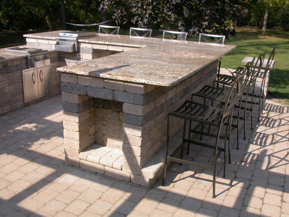 Modelo de patio actual de tamaño medio en patio trasero con cocina exterior y adoquines de ladrillo