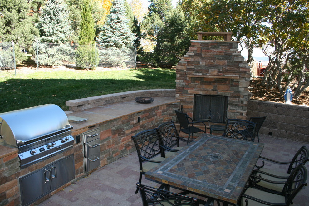 This is an example of a medium sized classic back patio in Denver with a fire feature, brick paving and no cover.