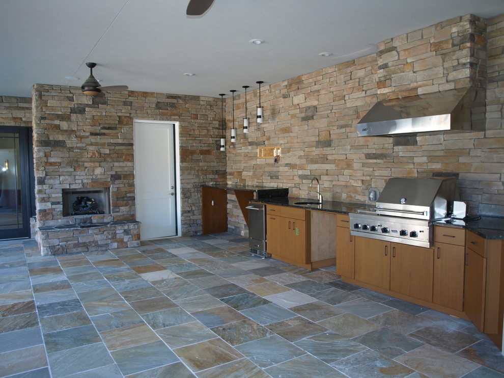 Large classic back patio in Charlotte with an outdoor kitchen, natural stone paving and a roof extension.