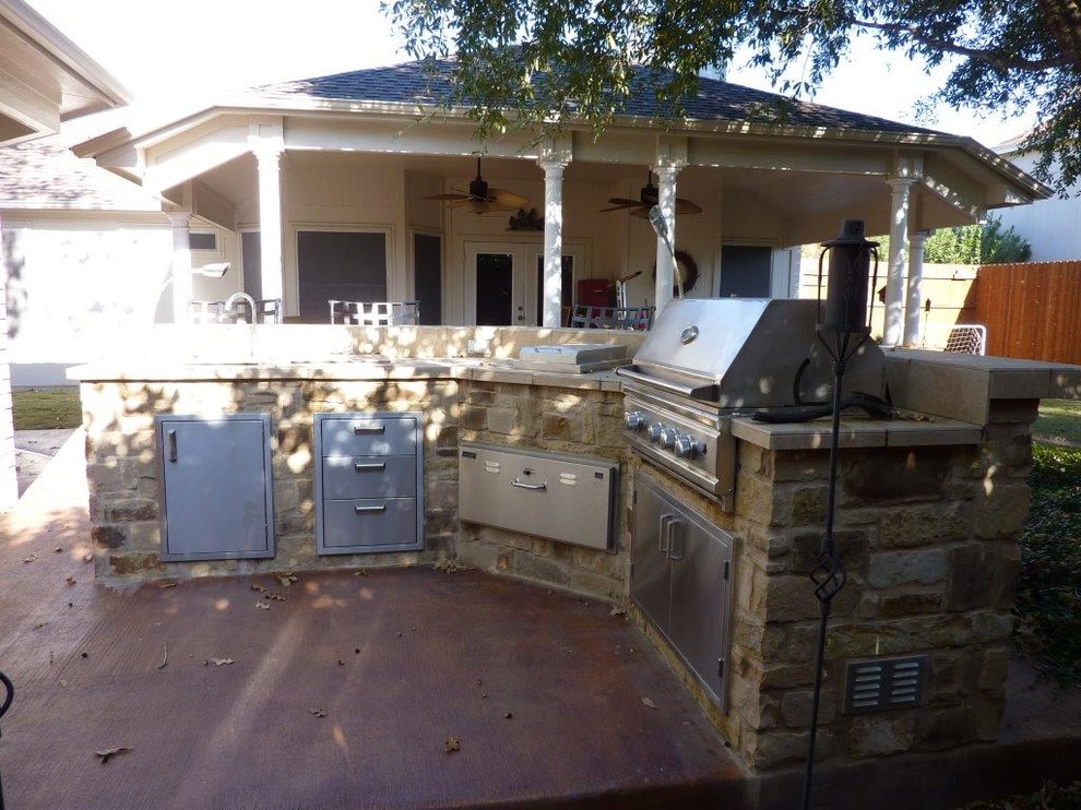 Réalisation d'une grande terrasse arrière tradition avec une cuisine d'été, une dalle de béton et une extension de toiture.