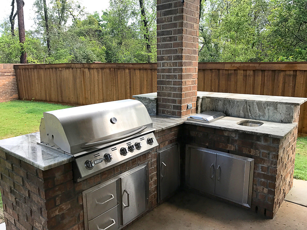 Example of a mid-sized classic backyard concrete patio kitchen design in Houston with a roof extension