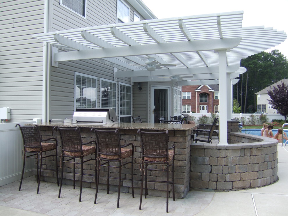 Aménagement d'une grande terrasse arrière classique avec une pergola, une cuisine d'été et une dalle de béton.