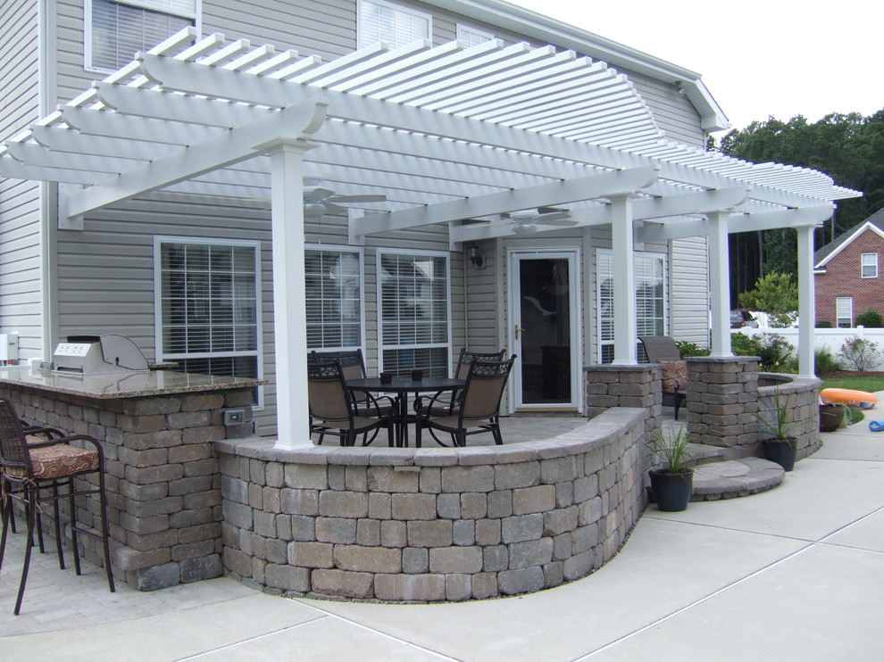Ejemplo de patio clásico grande en patio trasero con pérgola, cocina exterior y losas de hormigón