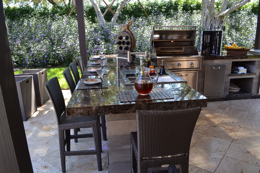 Example of a huge classic backyard stone patio kitchen design in Miami with a pergola