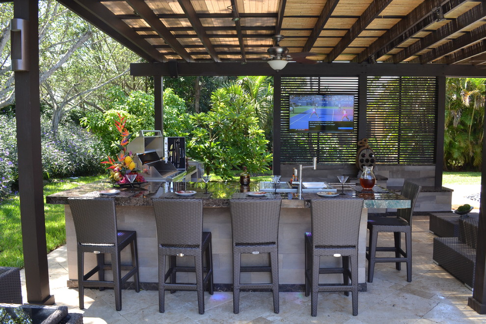 Photo of an expansive classic back patio in Miami with an outdoor kitchen, natural stone paving and a pergola.