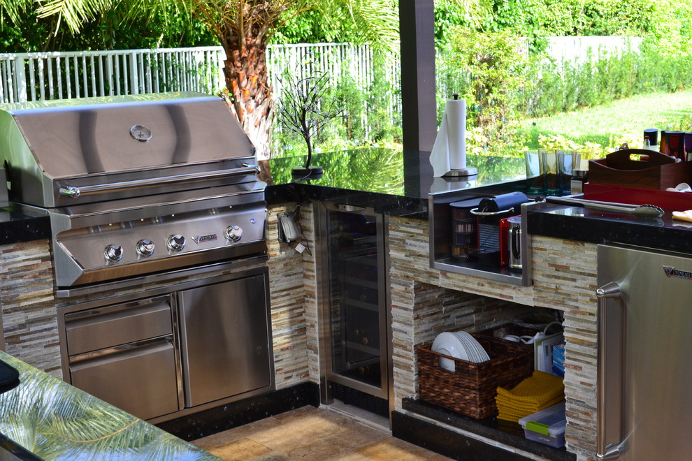 Photo of an expansive mediterranean back patio in Miami with an outdoor kitchen, natural stone paving and a pergola.